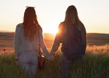 Two Women Holding Hands At Sunset In The Field