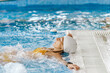 © Cavan Images - Beautiful woman wearing a swimming cap relaxing in a swimming pool