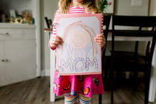 Young Girl Holding A Drawing She Made Of Her Mom For Mother's Day