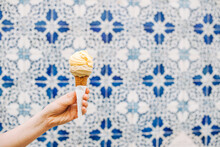 Female Hand Holding Ice Cream Cone On Blurred White Blue Background