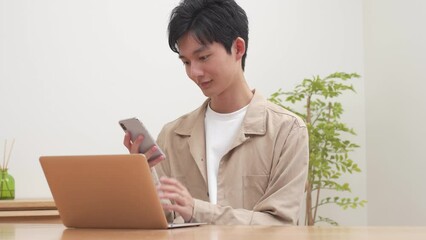 Sticker - パソコンを見ながら携帯で話す若い日本人男性