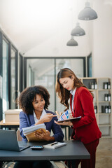 Two  businesswoman discuss investment project working and planning strategy with tablet laptop computer in modern office.