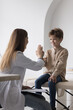 © fizkes - Positive patient boy visiting pediatrician in clinic office, giving high five to doctor, sitting on medical couch, smiling. Family practitioner clapping greeting hands with child after examination
