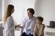 © fizkes - Serious pediatrician woman talking to focused father hugging little son. Dad and kid visiting doctor, listening diagnosis, treatment recommendation after medical checkup of child