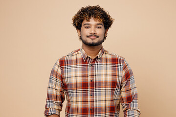Wall Mural - Confident satisfied cool student Indian man wearing checkered brown shirt casual clothes looking camera isolated on plain pastel light beige color background studio portrait. People lifestyle concept.