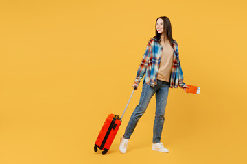 Canvas Print - Full body traveler woman wear casual clothes hold valise passport ticket look aside isolated on plain yellow background Tourist travel abroad in free time rest getaway Air flight trip journey concept