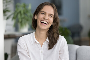 Cheerful pretty young woman home candid portrait. Happy joyful beautiful model with healthy white teeth posing at camera, looking away with toothy smile, laughing, feeling joy