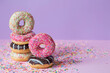 Delicious dessert. Pink, chocolate and white donuts with multicolored sprinkles on a purple background of Sweets. Confectionery products.