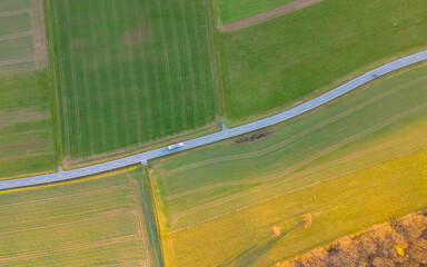 birds eye view of road going through green fields at sunset