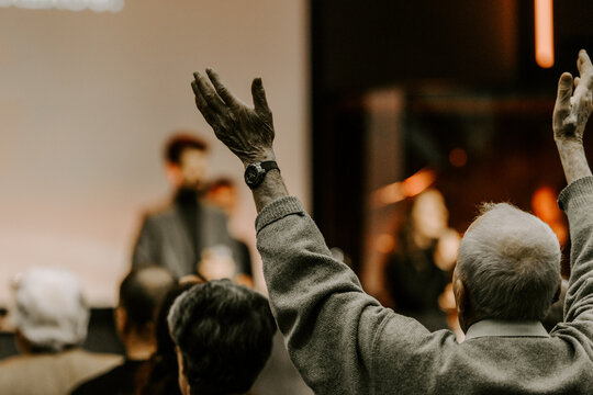 Elder man rise his hand while he is praise God at church service