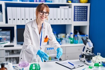 Poster - Young woman scientist smiling confident holding test tubes at laboratory