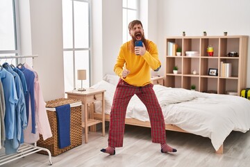 Sticker - Young redhead man singing song using smartphone at bedroom