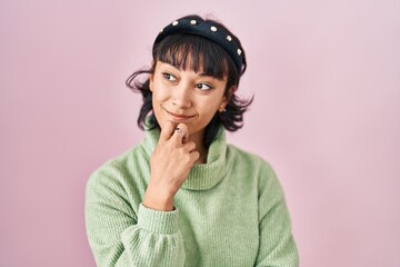 Poster - Young beautiful woman standing over pink background with hand on chin thinking about question, pensive expression. smiling and thoughtful face. doubt concept.