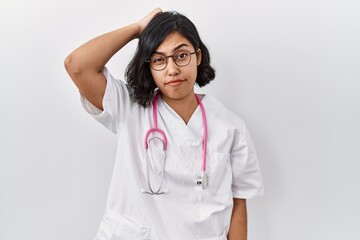 Sticker - Young hispanic doctor woman wearing stethoscope over isolated background confuse and wonder about question. uncertain with doubt, thinking with hand on head. pensive concept.