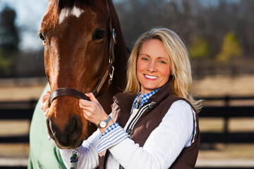 A Blonde Equestrian Model Feeds Her Horses Hay During A Sunny Morning