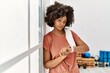 © Krakenimages.com - Young african american woman looking watch leaning on wall at sport center