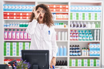 Sticker - Hispanic woman with curly hair working at pharmacy drugstore doing ok gesture shocked with surprised face, eye looking through fingers. unbelieving expression.