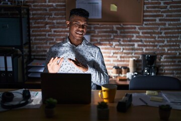 Wall Mural - Young hispanic man working at the office at night disgusted expression, displeased and fearful doing disgust face because aversion reaction. with hands raised