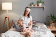 © sementsova321 - Indoor shot of attractive smiling happy woman in sleeping mask on her forehead and baby girl in bed at home, family having fun, enjoying the time spent together.