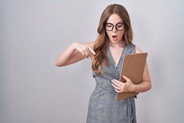 Wall Mural - Caucasian woman wearing glasses and business clothes pointing down with fingers showing advertisement, surprised face and open mouth