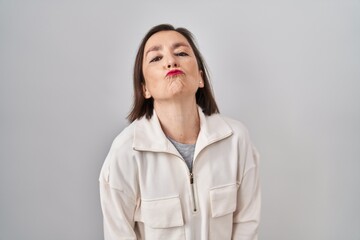 Sticker - Middle age hispanic woman standing over isolated background looking at the camera blowing a kiss on air being lovely and sexy. love expression.