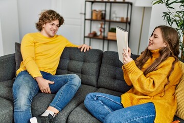 Sticker - Young caucasian couple smiling confident drawing portrait on notebook at home