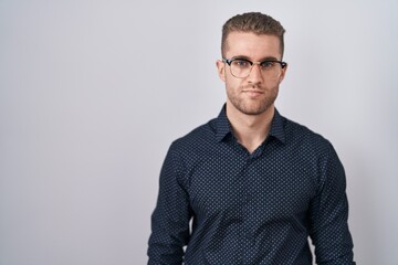 Wall Mural - Young caucasian man standing over isolated background relaxed with serious expression on face. simple and natural looking at the camera.