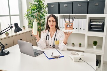 Sticker - Hispanic doctor woman holding model of human anatomical skin and hair relaxed with serious expression on face. simple and natural looking at the camera.