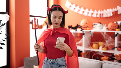 Sticker - Young beautiful hispanic woman wearing devil costume using smartphone at home