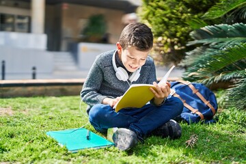 Poster - Blond child student reading book sitting on grass at park