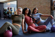© Flamingo Images - Sporty young women sitting with weights in a gym. Group of friends in gym