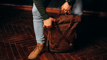 Wall Mural - man's hand holding a canvas backpack. Model wears a brown belt bag, Medium Leather Backpack Man Rolltop Leather Rucksack Bag