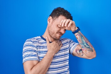 Poster - Young hispanic man standing over blue background touching forehead for illness and fever, flu and cold, virus sick