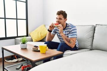 Wall Mural - Young hispanic man having breakfast at home