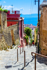 Wall Mural - Naples, Italy. View of a glimpse of the Gulf of Naples through the characteristic houses of the Petraio Steps. Vertical image. August 24, 2022.