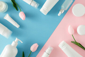 Wall Mural - Organic products concept. Flat lay photo of white cosmetics tubes, pump bottles, cream jars and tulips flowers on pastel pink and blue background with copyspace in the middle. Cosmetics mockup idea.