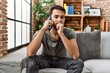 © Krakenimages.com - Young hispanic man worried talking on the smartphone at home
