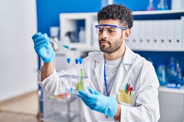 Poster - Young arab man wearing scientist uniform holding test tubes at laboratory