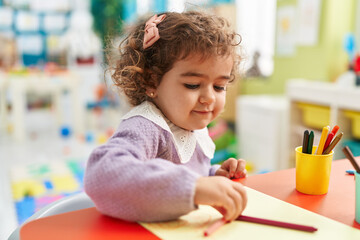 Sticker - Adorable hispanic girl preschool student sitting on table drawing on paper at kindergarten