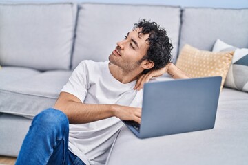 Canvas Print - Young hispanic man using laptop sitting on floor at home