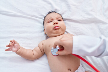 Wall Mural - Adorable hispanic toddler lying on bed having chest auscultation at bedroom