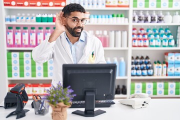 Sticker - Hispanic man with beard working at pharmacy drugstore smiling with hand over ear listening an hearing to rumor or gossip. deafness concept.