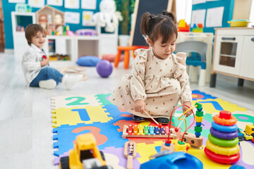 Canvas Print - Two kids playing with dolls sitting on bed at kindergarten