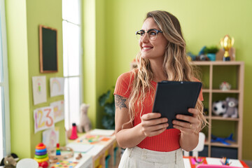 Sticker - Young blonde woman teacher using touchpad standing at kindergarten