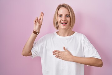 Sticker - Young caucasian woman standing over pink background smiling swearing with hand on chest and fingers up, making a loyalty promise oath