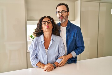 Wall Mural - Middle age couple standing together looking at the camera blowing a kiss on air being lovely and sexy. love expression.