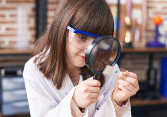 Poster - Adorable hispanic girl student looking sample using magnifying glass at laboratory classroom