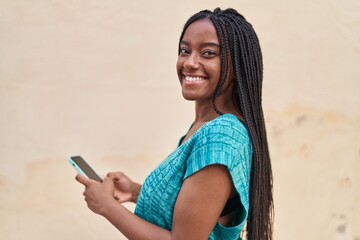 Wall Mural - African american woman smiling confident using smartphone at street