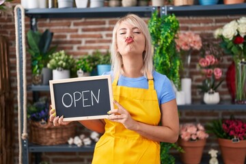 Poster - Young caucasian woman working at florist holding open sign looking at the camera blowing a kiss being lovely and sexy. love expression.