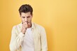 © Krakenimages.com - Young hispanic man standing over yellow background feeling unwell and coughing as symptom for cold or bronchitis. health care concept.